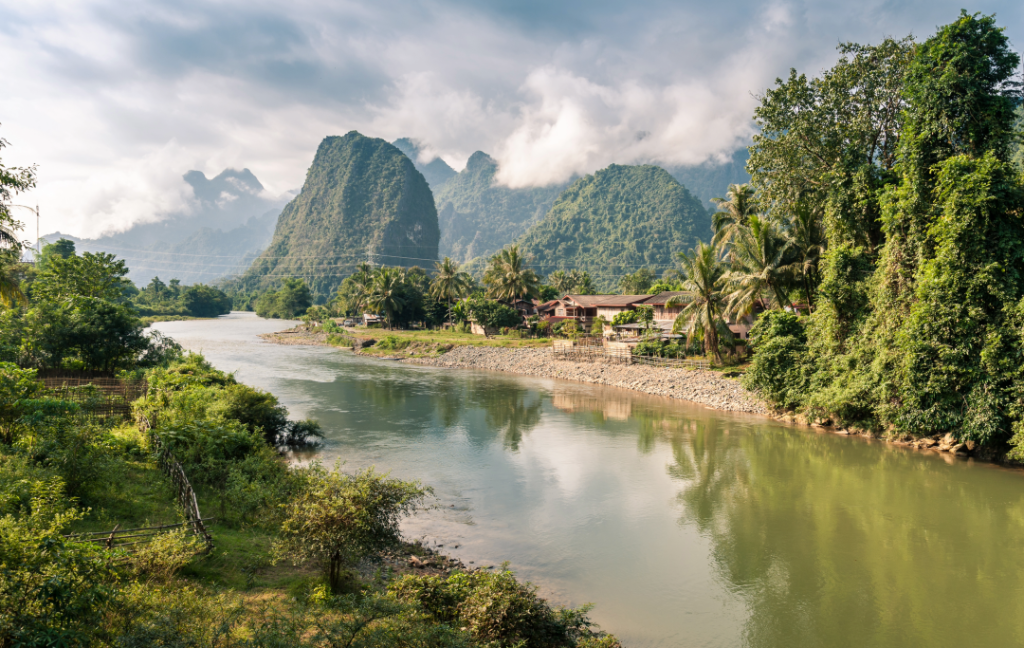 Image shows landscape in Laos with mountains in background and water in foreground